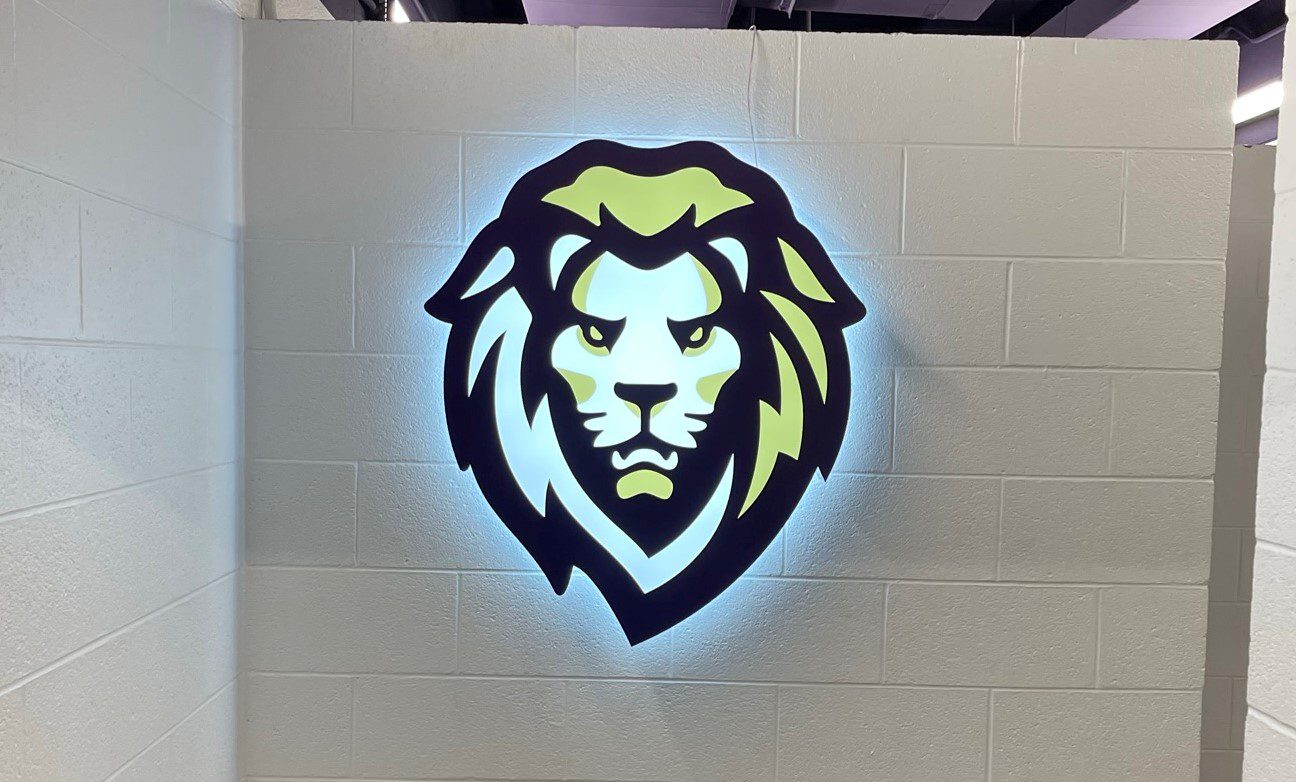 Illuminated lion head logo with glowing effect on a white brick wall.