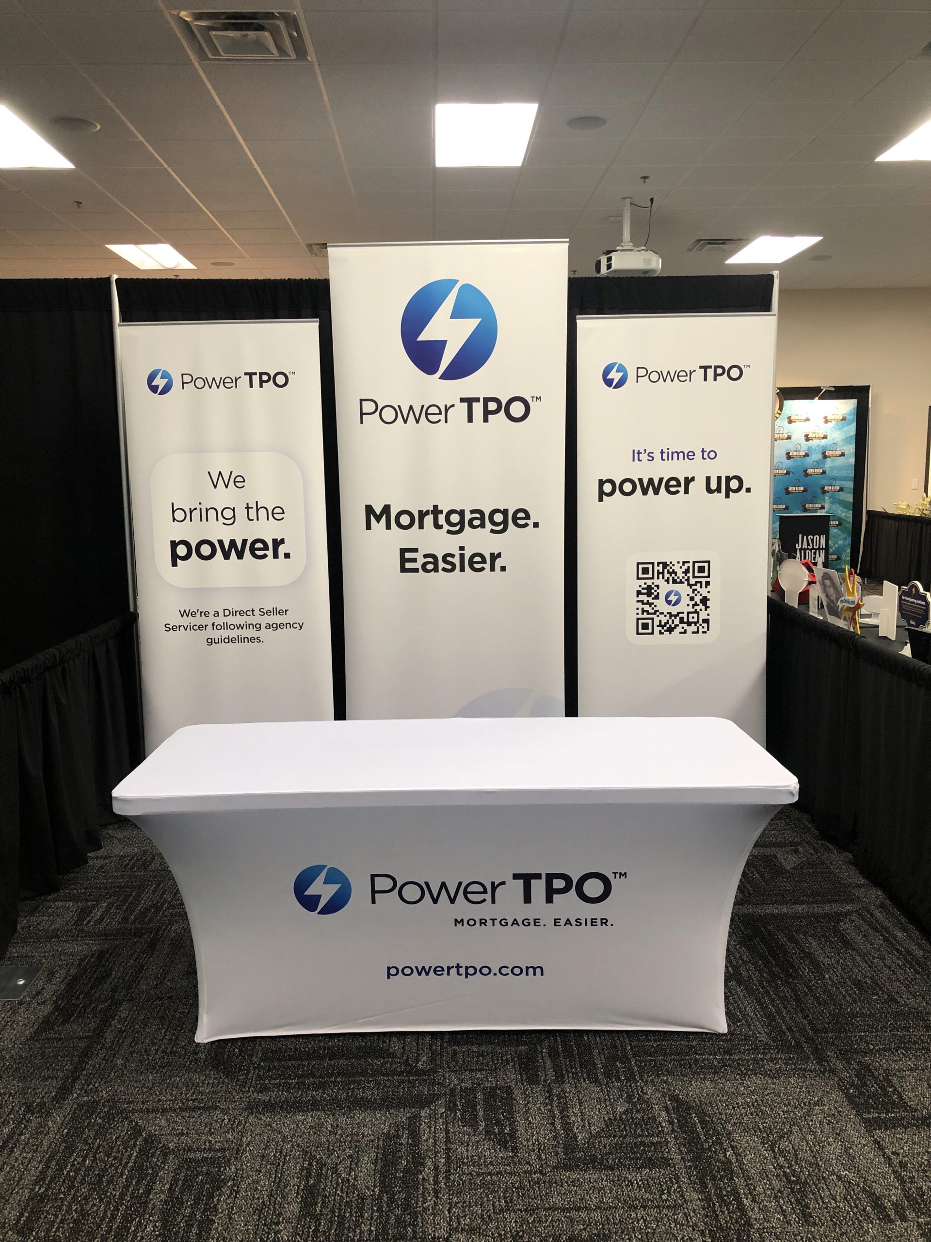 A custom white tablecloth featuring the company's logo printed on the front, designed to fit the table perfectly.
