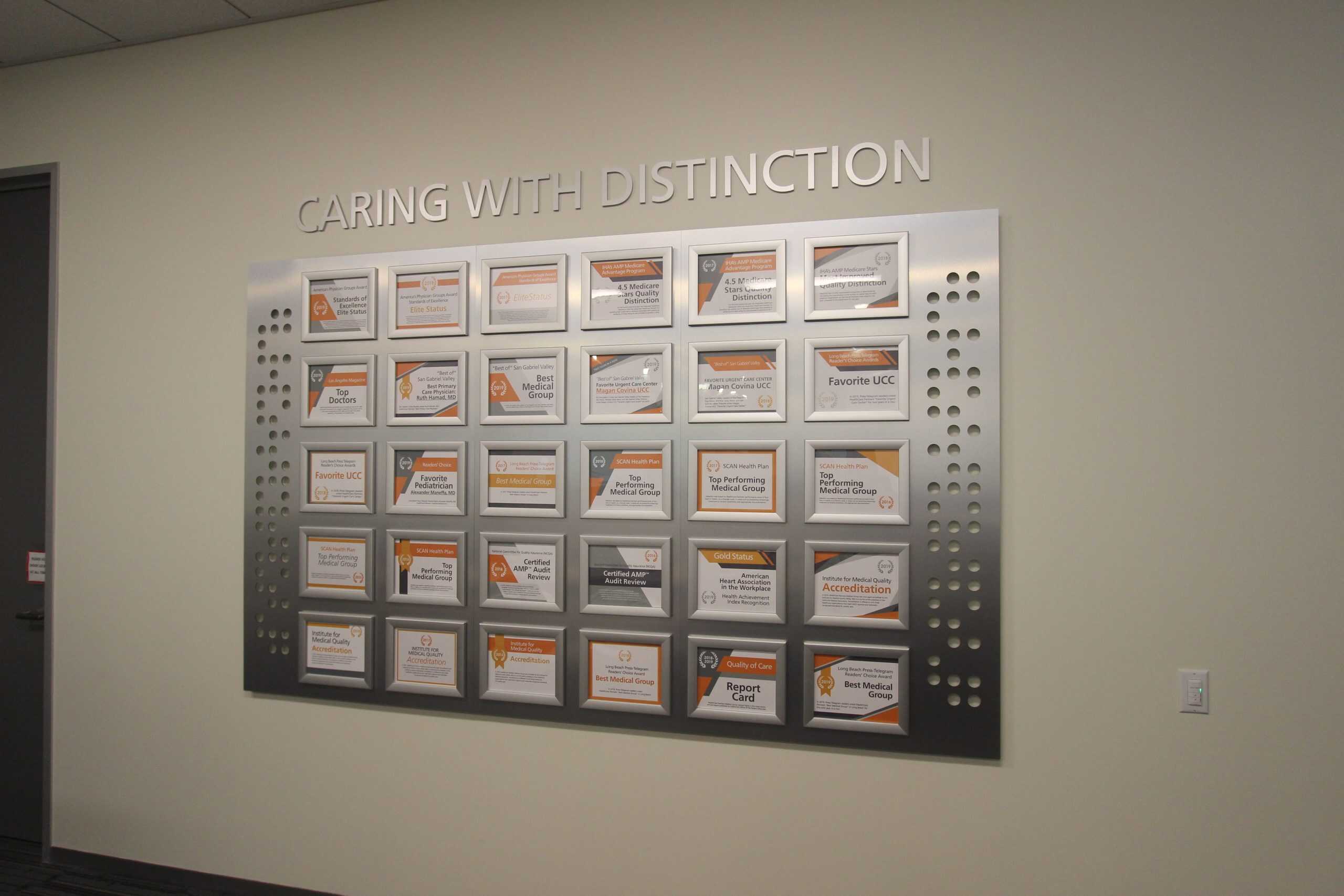 Office decor wall crafted from CNC-routed brushed silver aluminum, featuring 3D letters and interchangeable frames for updating company awards.