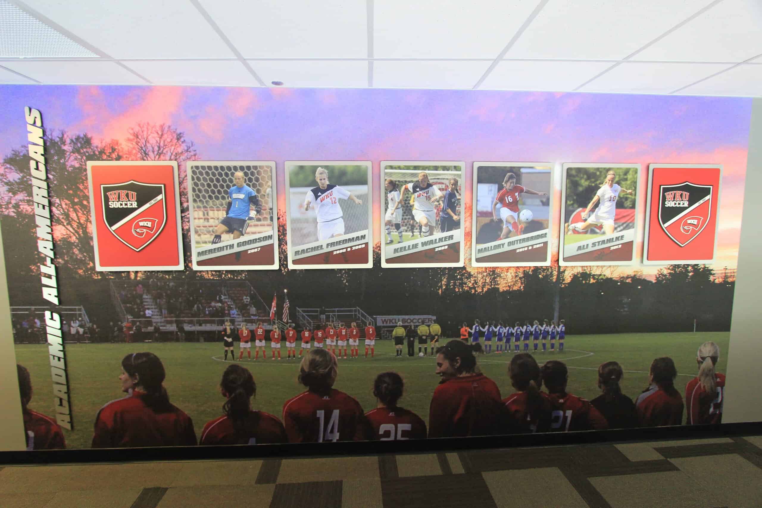 Athletic posters of All-American players displayed atop brushed silver dibond to add depth over a custom large photographic wall mural.